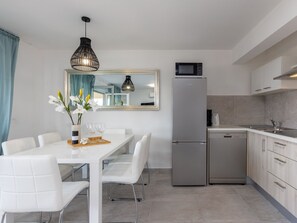Eine moderne Küche mit einem weißen Esstisch, Stühlen, einem Kühlschrank und einer Mikrowelle.