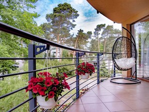 A balcony with a metal railing, potted red flowers, and a hanging chair. - Apartment Nr. 6 by Interhome (Pobierowo)