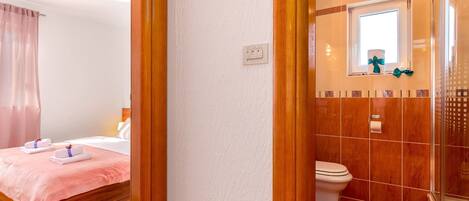 Una habitación de hotel con cama, baño con ducha y ventana.