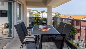 Ein Balkon mit Tisch für zwei Personen, gedeckt mit Pizza und Weingläsern.