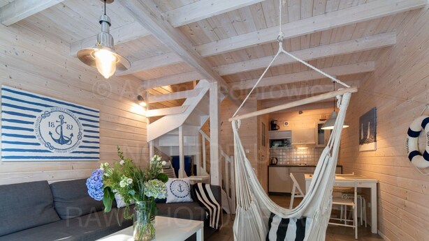 A cozy interior with a hanging chair, a sofa, a coffee table, and a kitchen area. - Marine Cottages mit Hund by Interhome (Pobierowo)