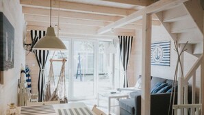 A cozy living room with a sofa, a coffee table, and a dining area with a table and chairs. There is a staircase leading to another level. - Marine Cottages mit Hund by Interhome (Pobierowo)