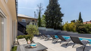 Ein Poolbereich mit Liegestühlen, einem Tisch mit Büchern und einem kleinen Baum.
