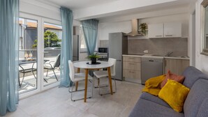 Ein kompakter Wohnbereich mit Essplatz, Küchenzeile und einer Couch mit Kissen.