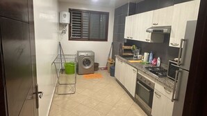 A compact kitchen with a washing machine, a microwave, and a stove. - Residence Ennassr 3 by Interhome (Agadir)