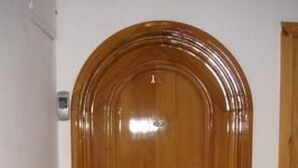 Una puerta de madera con un picaporte de metal y un pequeño ventanal arriba.