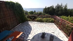 Un patio con piso de piedra, una mesa con mantel floral y vista al mar.