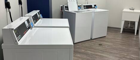 A laundry room with two front-loading washing machines, a sink, and a blue wall.