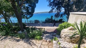 A stone pathway leading to a scenic view of the sea, surrounded by lush greenery and a stone wall. - Wohnung 10m vom Strand entfernt by Interhome (Crikvenica)