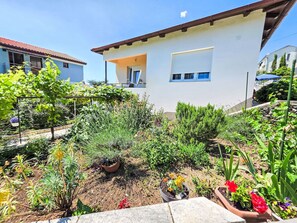A residential building with a garden in front, a balcony, and a clear blue sky. - Wohnung für 7 Personen, 100m vom Strand by Interhome (Crikvenica)
