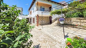 A two-story house with a stone facade, a tiled patio, and a garden with potted plants. - Wohnung für 7 Personen, 100m vom Strand by Interhome (Crikvenica)