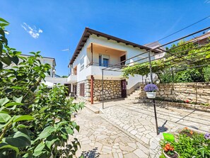 A two-story house with a stone facade, a tiled patio, and a garden with potted plants. - Wohnung für 7 Personen, 100m vom Strand by Interhome (Crikvenica)