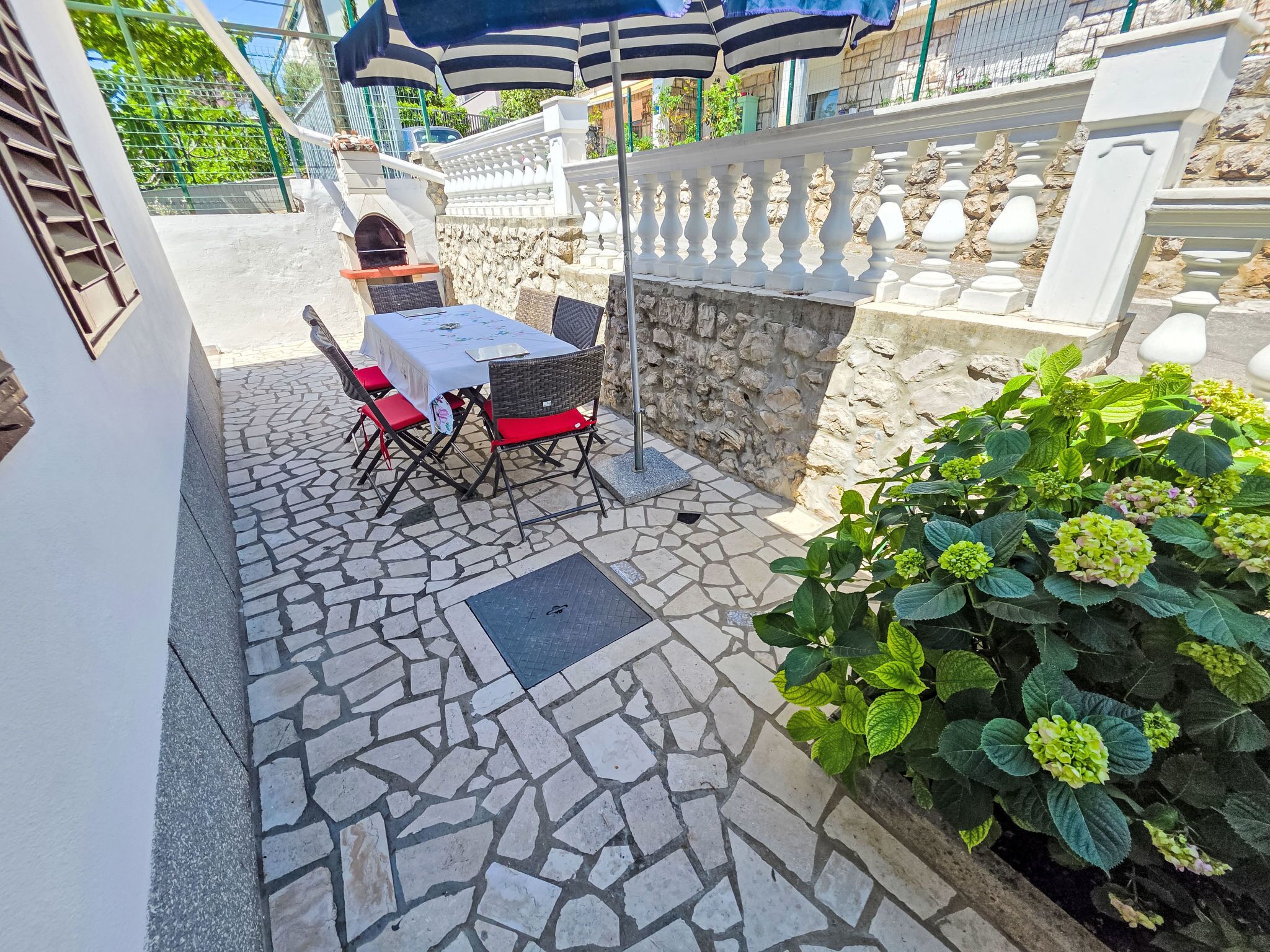 Un patio con una mesa y sillas, piso de piedra, pared de piedra y una planta.