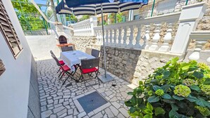 A patio with a table and chairs, a stone floor, a stone wall, and a plant. - Wohnung für 7 Personen, 100m vom Strand by Interhome (Crikvenica)