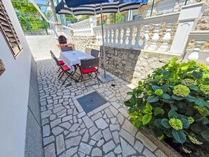A patio with a table and chairs, a stone floor, a stone wall, and a plant. - Wohnung für 7 Personen, 100m vom Strand by Interhome (Crikvenica)