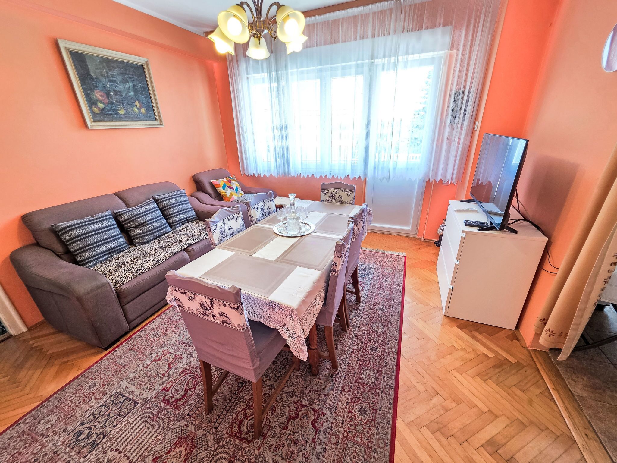 A living room with a sofa, a dining table, and a television.