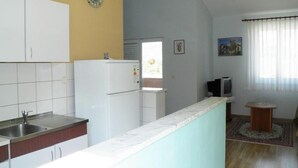 Una cocina compacta con armarios blancos, un lavamanos integrado y un refrigerador.