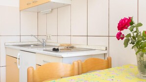 Eine kleine Küche mit Spüle, Herd und Tisch mit Blumenmuster-Tischdecke.