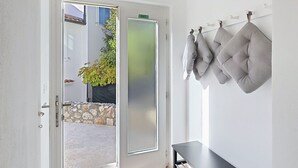 Ett modernt rum med en glasdörr som leder ut till ett utomhusområde, en svart bänk och en kudde som är fäst på väggen.