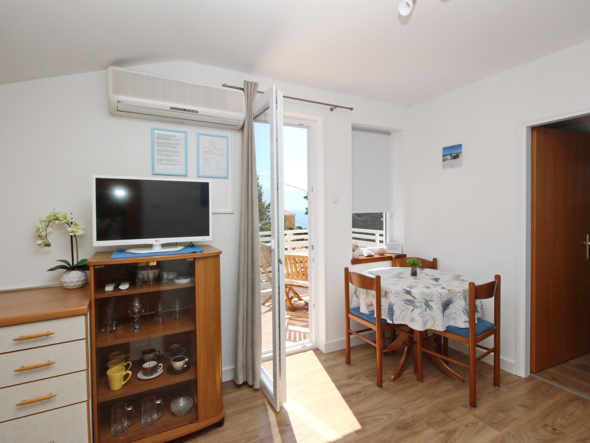 A compact living space with a TV, wooden cabinet, dining table, and chairs.