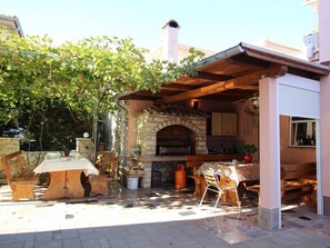 Ett utomhuskök med en stenugn, trämöbler och en pergola.