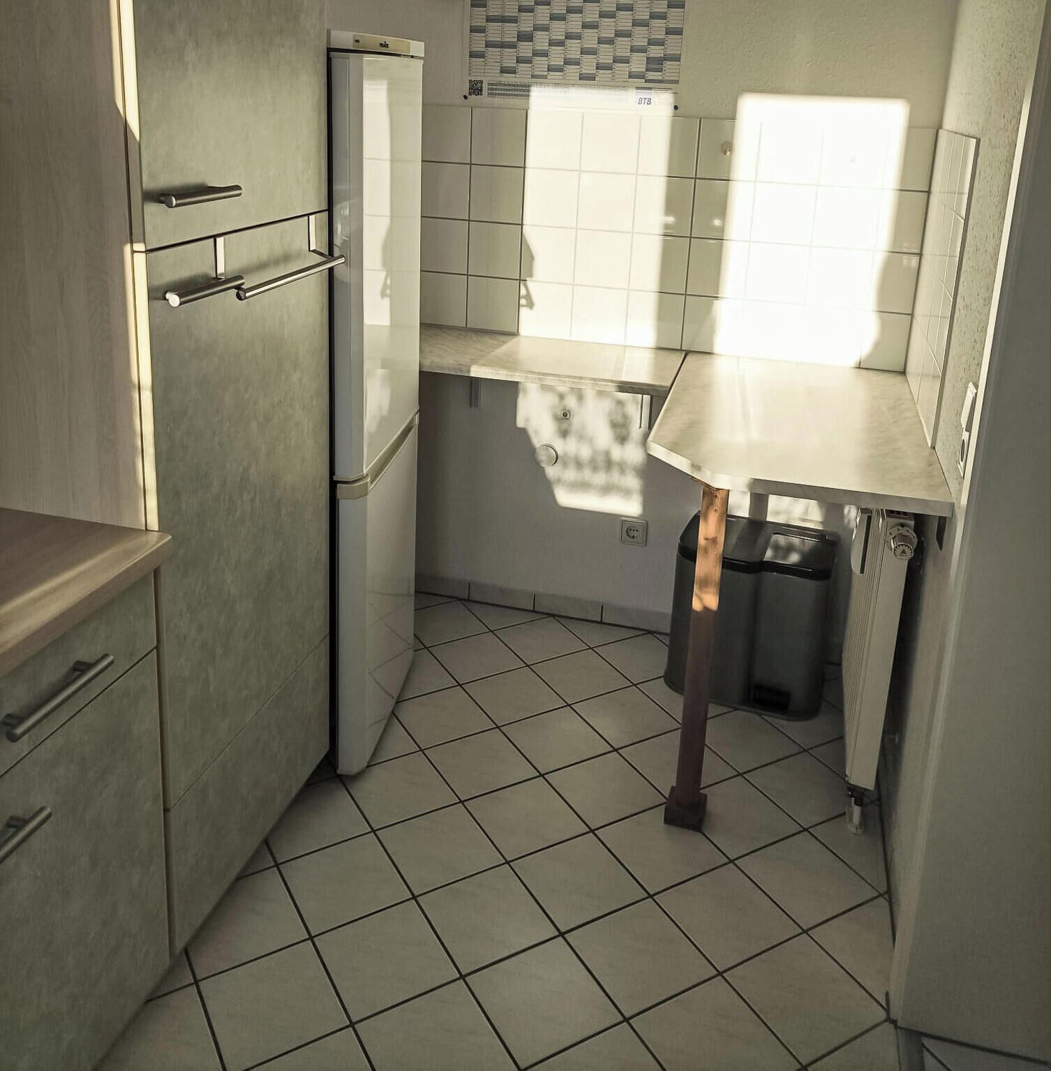 A compact kitchen with a refrigerator, a sink, and a window.