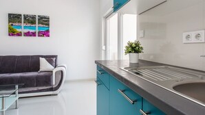 Eine moderne Küche mit Türkis-Schränken, einer Edelstahl-Spüle und einem Glastisch.