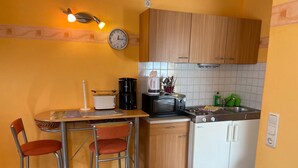 A compact kitchen with a dining area, including a table, chairs, a coffee maker, a toaster, and a microwave. - Überdachte Terrasse by Interhome (Baabe)