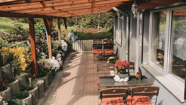 A covered patio with outdoor seating, a brick pathway, and a garden with various plants. - Überdachte Terrasse by Interhome (Baabe)