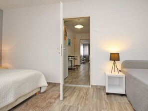 Habitación de hotel con dos camas, una mesita con una lámpara y vista al comedor.