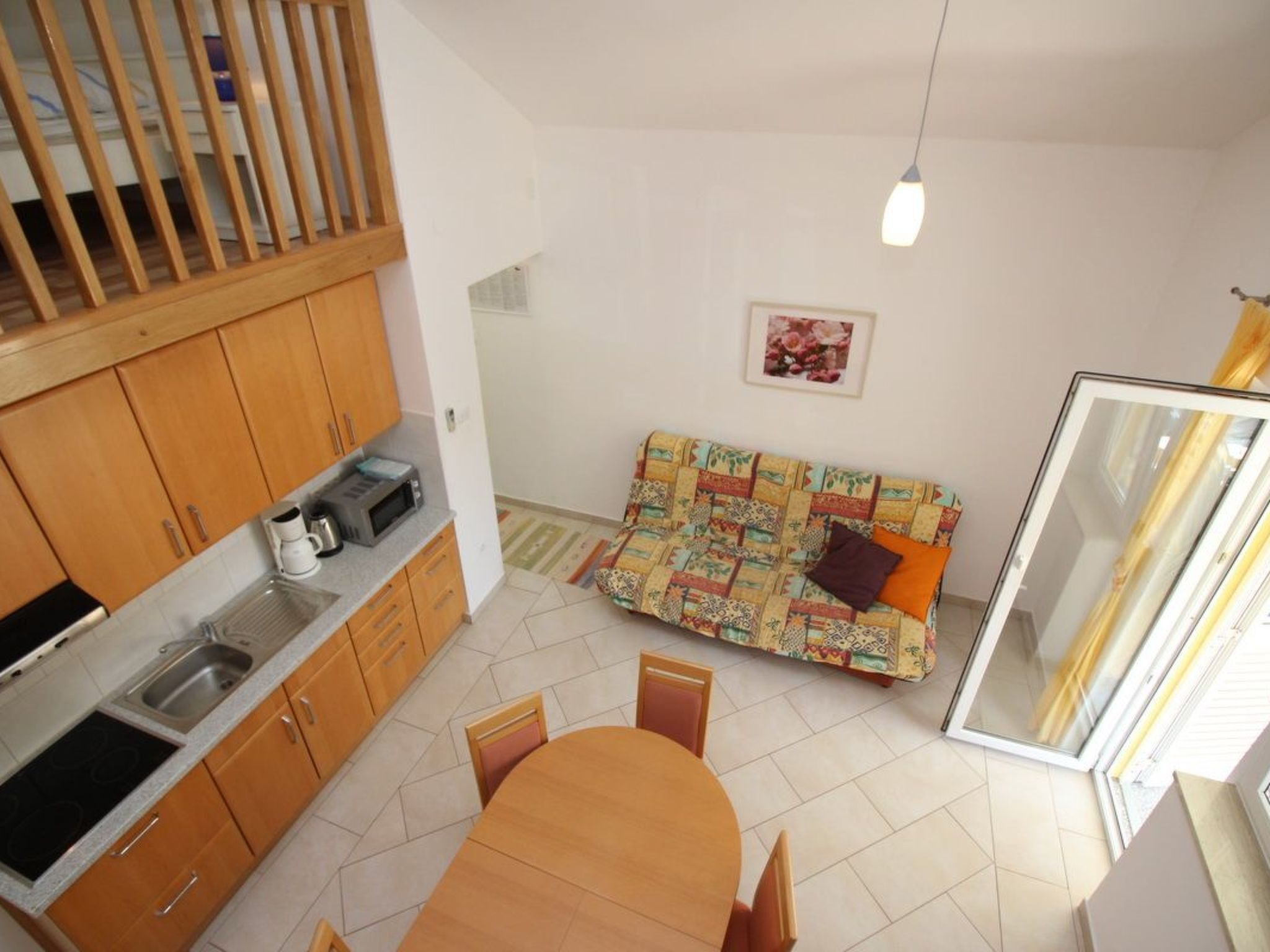 Cocina compacta con armarios de madera, una mesa de comedor y un sofá.
