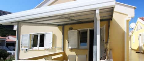 A two-story building with a covered outdoor area, a balcony, and a door leading to an interior space.