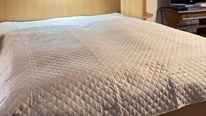 Een slaapkamer met een bed, een houten hoofdbord, inbouwplanken, een televisie en een ingelijst schilderij aan de muur.