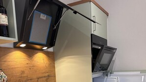 Een kleine keuken met een ingebouwde vaatwasser, een magnetron en een koelkast.