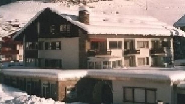 Een meerhoog gebouw met een met sneeuw bedekte dak, gelegen in een bergachtig gebied.