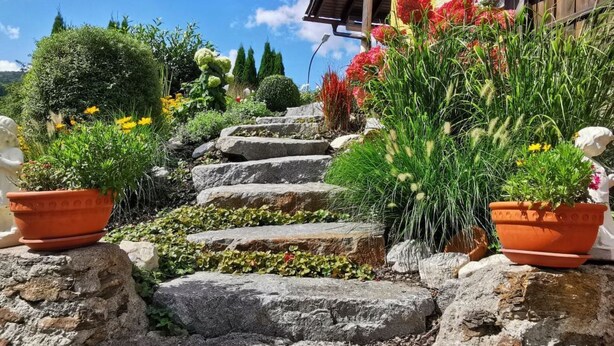 A stone staircase leading to a wooden building with terracotta pots and potted plants on either side. - Fewo im OG mit Balkon by Interhome (Gleißenberg)