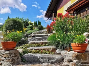 A stone staircase leading to a wooden building with terracotta pots and potted plants on either side. - Fewo im OG mit Balkon by Interhome (Gleißenberg)