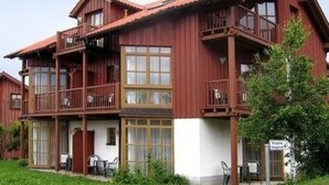 A two-story wooden building with balconies, large windows, and a sign indicating a restaurant. - Dream Apartment by Interhome (Rötz)
