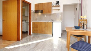 A compact kitchen with wooden cabinets, a built-in oven, and a small refrigerator. - Appartement in Baška mit Eigenem Balkon by Interhome (Krk/Baška)
