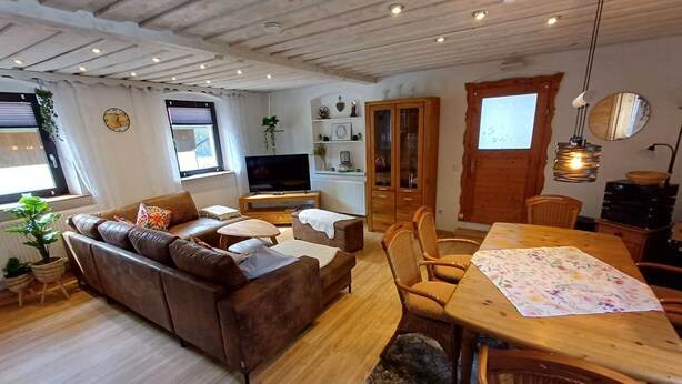 Una sala acogedora con un sofá de cuero marrón, una mesa de comedor de madera y un televisor.