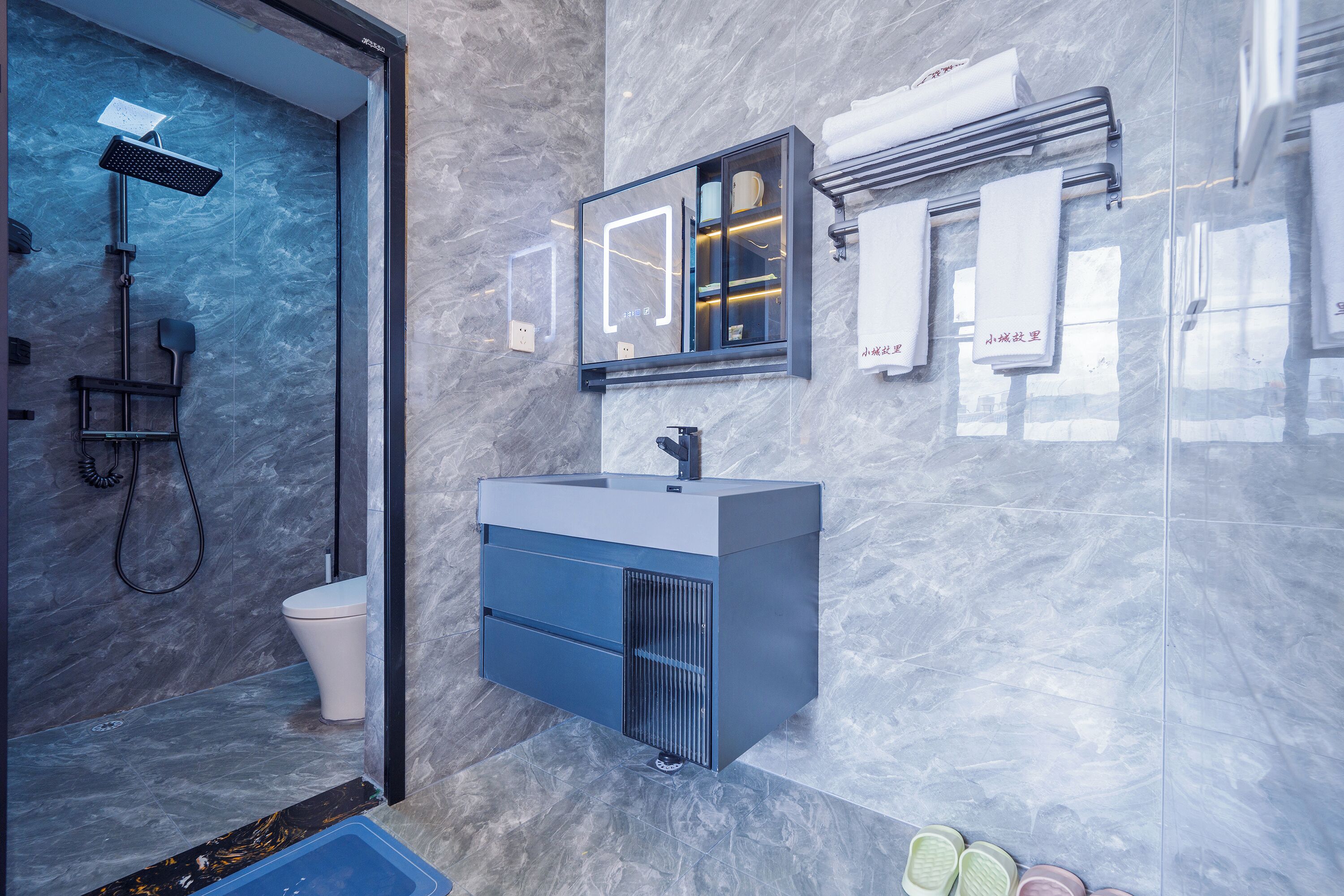 A modern bathroom with a shower, toilet, vanity, and towel rack.