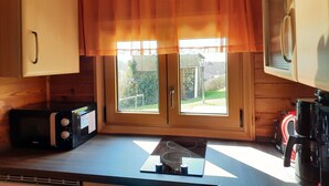 Een keuken met houten kastjes, een magnetron, een fornuis en een koffiezetapparaat.