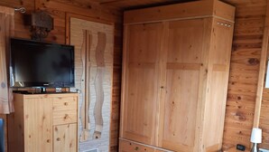 Een houten kamer met een bed, een televisie op een houten kast en een kledingkast.