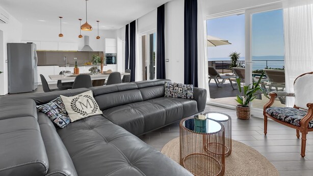 A modern living room with a grey sectional sofa, a dining area, and a balcony with outdoor seating. - Villa inmitten der Natur in ruhiger Lage by Interhome (Makarska)