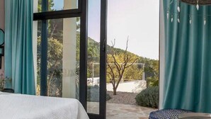 A bedroom with a bed, a large sliding glass door leading to a patio, and a view of a tree and a building in the distance. - Stylische Villa -Tres Chic- in Makarska by Interhome (Makarska)