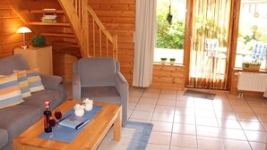 Un interior de madera con un sofá, un sillón y una mesa con una botella y vasos.