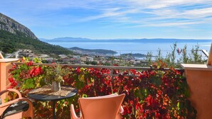 A terrace with a table and chairs, overlooking a coastal town and the sea. - Bella Vista by Interhome (Makarska)