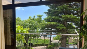 En balkon med gelænder, en plantekasse og udsigt over have og træer.