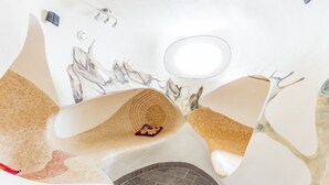 Ein Badezimmer mit einzigartigem Design, ausgestattet mit einem gewölbten Waschbecken, einem kleinen roten Dekorationsobjekt und einem gefliesten Boden.