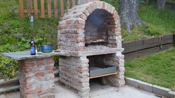 A brick-built outdoor oven with a table in front, a bottle, and a bowl. - Almhaus am Hohenwart by Interhome (Klippitztörl)